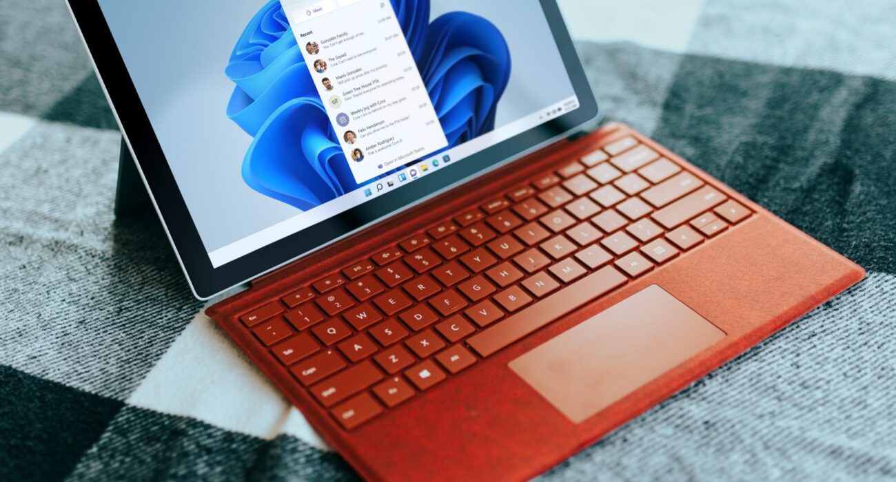 Red Surface laptop on a checkered bed by a window