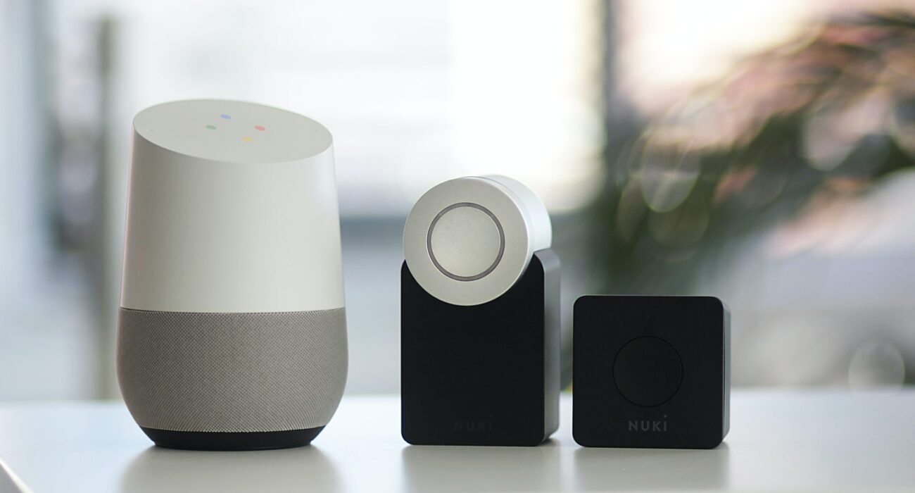 white and gray Google smart speaker and two black speakers