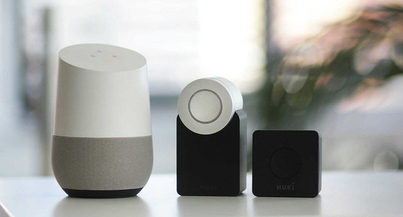 white and gray Google smart speaker and wo black speakers